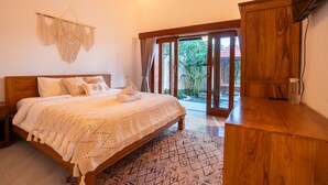 A bedroom with a wooden bed, a large window, and a wooden wardrobe. - Authentic Balinese design with modern touches (Bali)
