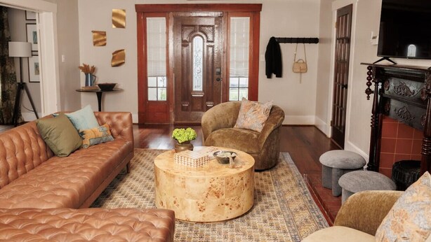 A living room with a brown leather sofa, a round coffee table, and a brown armchair. - Montrose Home walkable neighborhood | Pet-friendly (Houston)