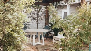 A garden pathway leading to a white house with a wooden pergola overhead. - Montrose Home walkable neighborhood | Pet-friendly (Houston)