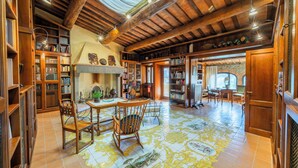 Una biblioteca amplia con estanterías de madera, una chimenea y un comedor con sillas y una mesa.