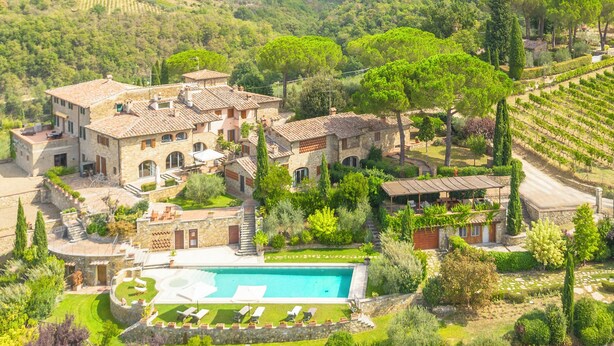 Una villa con piscina, rodeada de exuberante vegetación y viñedos.