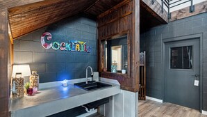 Une cuisine avec un évier encastré, un plafond en bois et une enseigne sur laquelle on peut lire « Cocktails ».