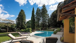Ein Garten mit Pool, Liegestühlen und einer Pergola.