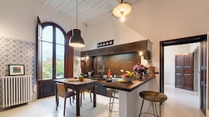 Eine moderne Küche mit Ziegelrückwand, Holzschränken und einem großen Fenster mit Blick ins Freie.
