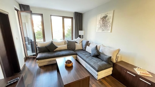 Una sala de estar moderna con un sofá modular, una mesa de centro y un tablero de ajedrez sobre una mesita auxiliar.