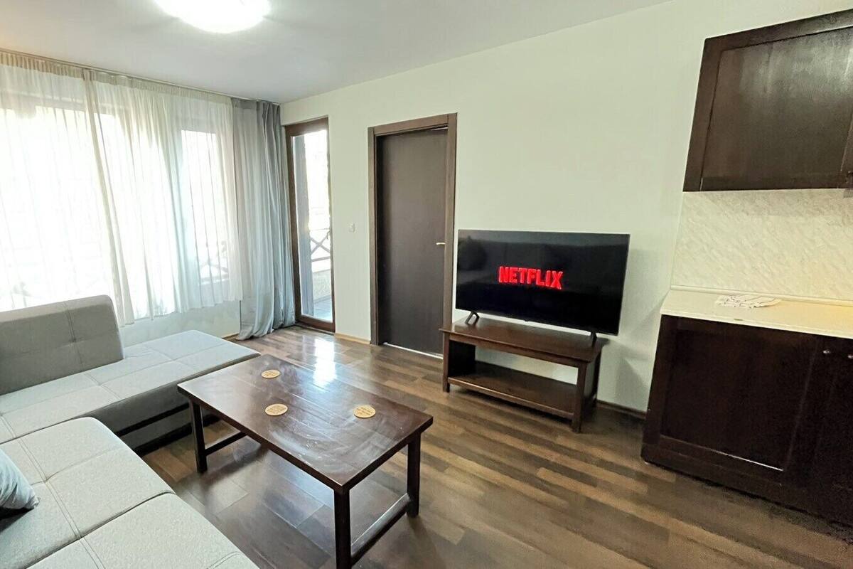 Ein Wohnzimmer mit einer Couch, einem Couchtisch und einem Fernseher, der 'NETFLIX' anzeigt.