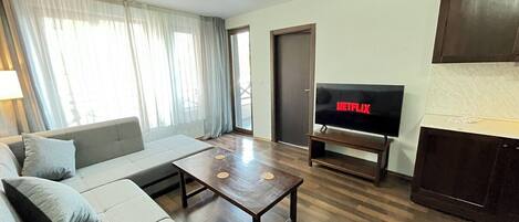 A living room with a sofa, coffee table, and a TV displaying 'NETFLIX'.