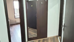 Un pasillo con piso de madera, un armario de madera oscura y un espejo.