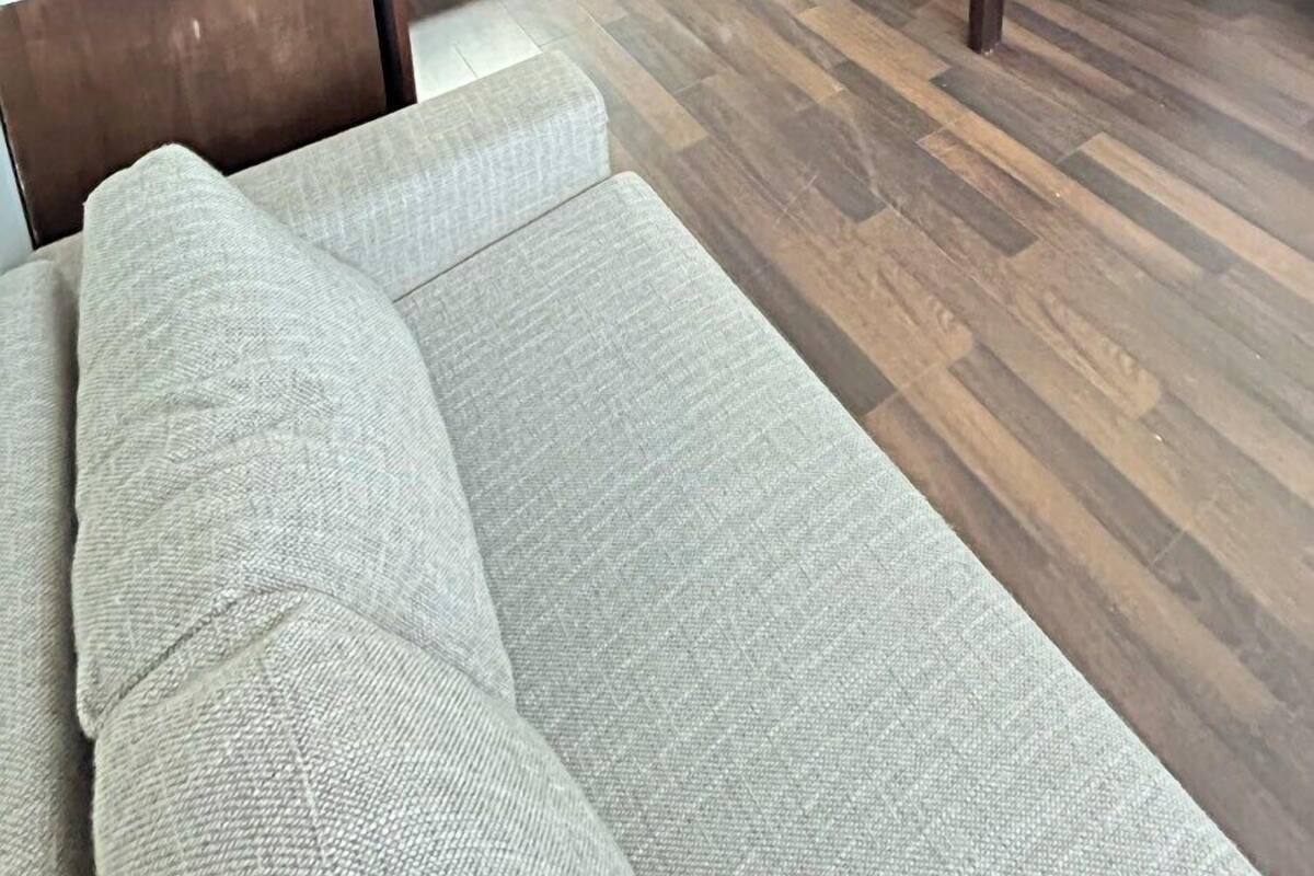 Ein modernes Wohnzimmer mit einer Couch, einem Esstisch und einer Küche im Hintergrund.
