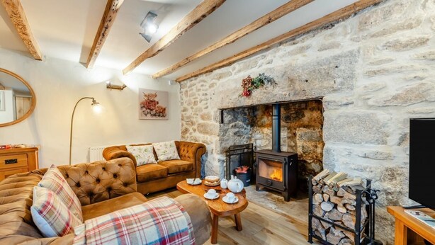 A cozy living room with a stone fireplace, a sofa, a plaid blanket, and a table with tea set.