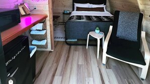 A cozy, wooden-paneled room with a bed, a desk, and a chair. - The Bike Inn (Bentonville)