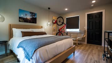 Ein Schlafzimmer mit Bett, einem an der Wand befestigten Fahrrad, einem Sessel und einer Tür.