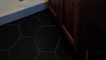 Un baño moderno con ducha, lavamanos y tocador.