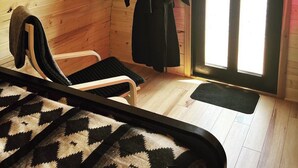 A cozy room with a bed, a chair, a robe hanging on a rack, and a door leading outside. - The Bike Inn (Bentonville)
