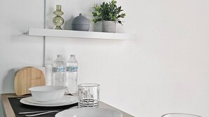 A dining table with white plates, bowls, and cutlery, flanked by two water bottles and a glass.