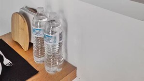A shelf with framed pictures, a candle, a plant, and water bottles.
