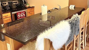 A kitchen with wooden cabinets, a stainless steel refrigerator, a microwave, and a coffee maker. There is a sign on the wall that reads "Ski Patrol" and another that says "Bed & Breakfast." - Ski in/out @Base Lodge at  Clock tower,Okemo. Building B  Ground Level sleeps 6 (Ludlow)