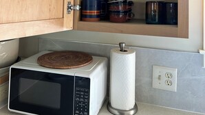 Una cocina con armarios de madera, microondas, una cesta y un rollo de toallas de papel.