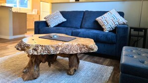 Una sala de estar moderna con un sofá azul, cojines estampados y una mesa de centro de madera original.