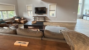 En rummelig stue med en stor sofaseng, et sofabord og et fladskærms-tv monteret på væggen.