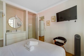 A hotel room with a bed, a chair, a television, a mirror, and a wardrobe.