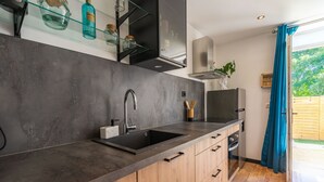 Eine moderne Küche mit einem schwarzen Spülbecken, Holzschränken und einer Glasablage mit Flaschen.