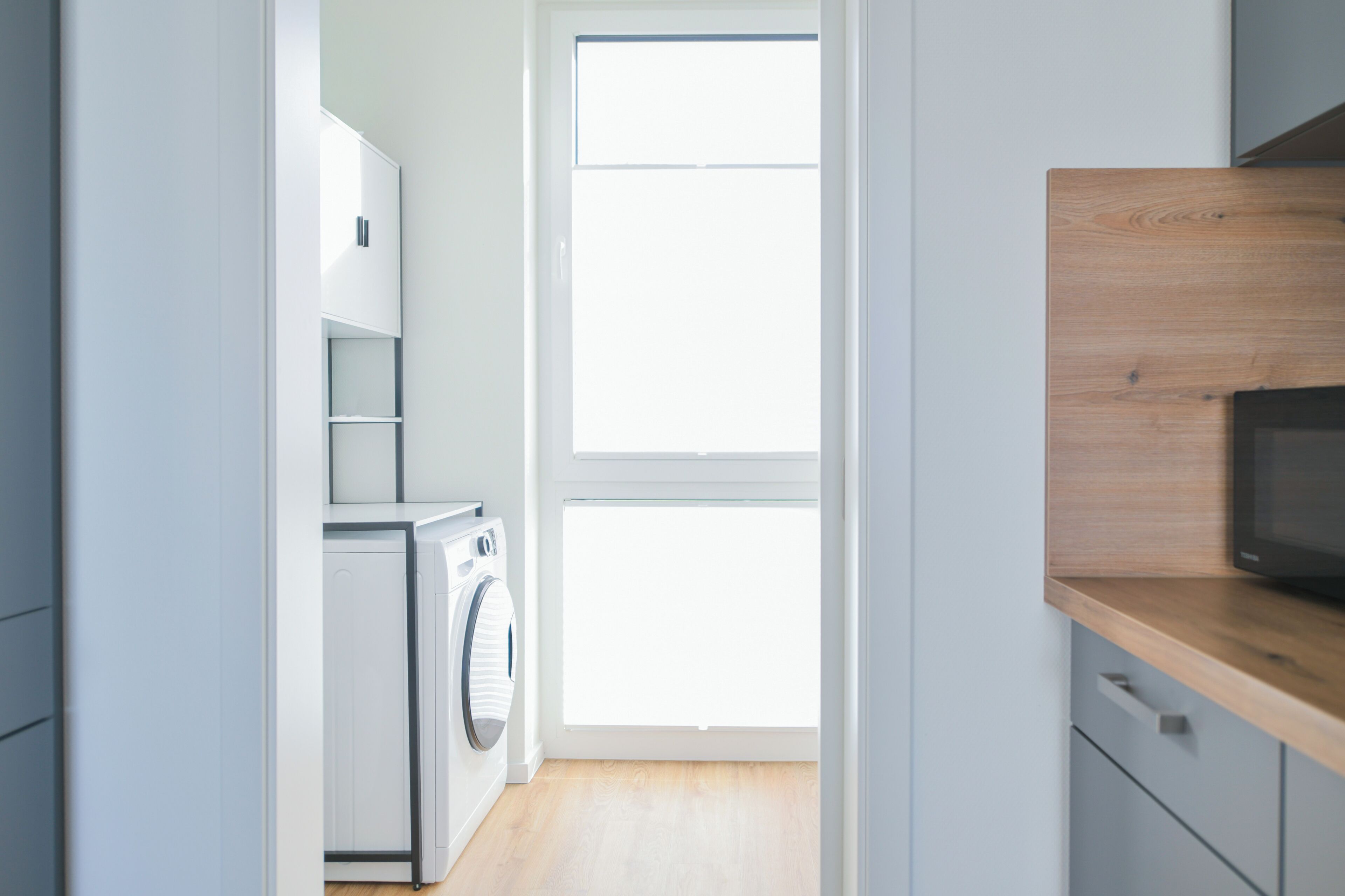Una cocina moderna con lavadora, microondas y ventana.