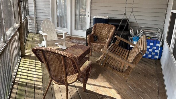A covered patio with wicker furniture, a swing chair, and a grill area. - Anchored At Last 3-bed Condo Kill Devil Hills w/ Large Deck and View of the Pool (Kill Devil Hills)