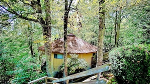 A treehouse with a wooden staircase leading up to it, surrounded by dense forest. - Sugar's Edge Luxury Mountain Treehouse with AirCon (Sugar Mountain)