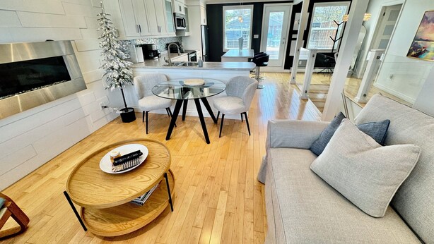 A modern living room with a grey sofa, a round wooden coffee table, and a dining area with a glass table and chairs. - Cozy, Relaxing, Center City Retreat with Private Rooftop Deck! (St. John's)