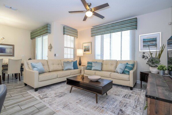A living room with a sectional sofa, a coffee table, and a ceiling fan.