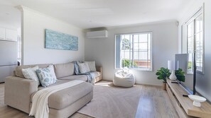 Relax in this stylish living space with a beige sofa, white bean bag chair, and flat-screen TV.