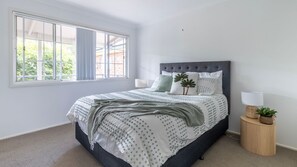 Relax in a serene space with a large bed and a view of lush greenery outside.