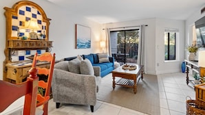 A living room with a blue sofa, a wooden coffee table, and a red chair. - Beach, Indoor and Outdoor Pools, Hot tub, Tennis walk Coligny Plaza! (Hilton Head Island)