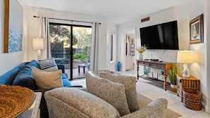 A living room with a sofa, armchairs, a TV, and a dining area with a table and chairs. - Beach, Indoor and Outdoor Pools, Hot tub, Tennis walk Coligny Plaza! (Hilton Head Island)