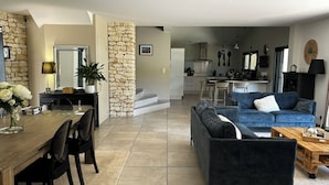 Amplia sala de estar con mesa de comedor, sofás y cocina al fondo.