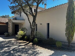 Un edificio moderno con entrada de piedra, un patio cubierto y un camino de acceso de grava.