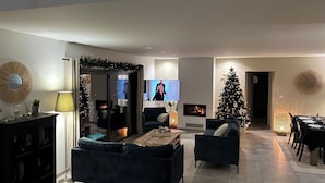 Una sala de estar moderna con chimenea, televisor y un árbol de Navidad.
