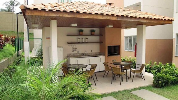 An outdoor kitchen area with a tiled roof, a dining table with chairs, and potted plants.