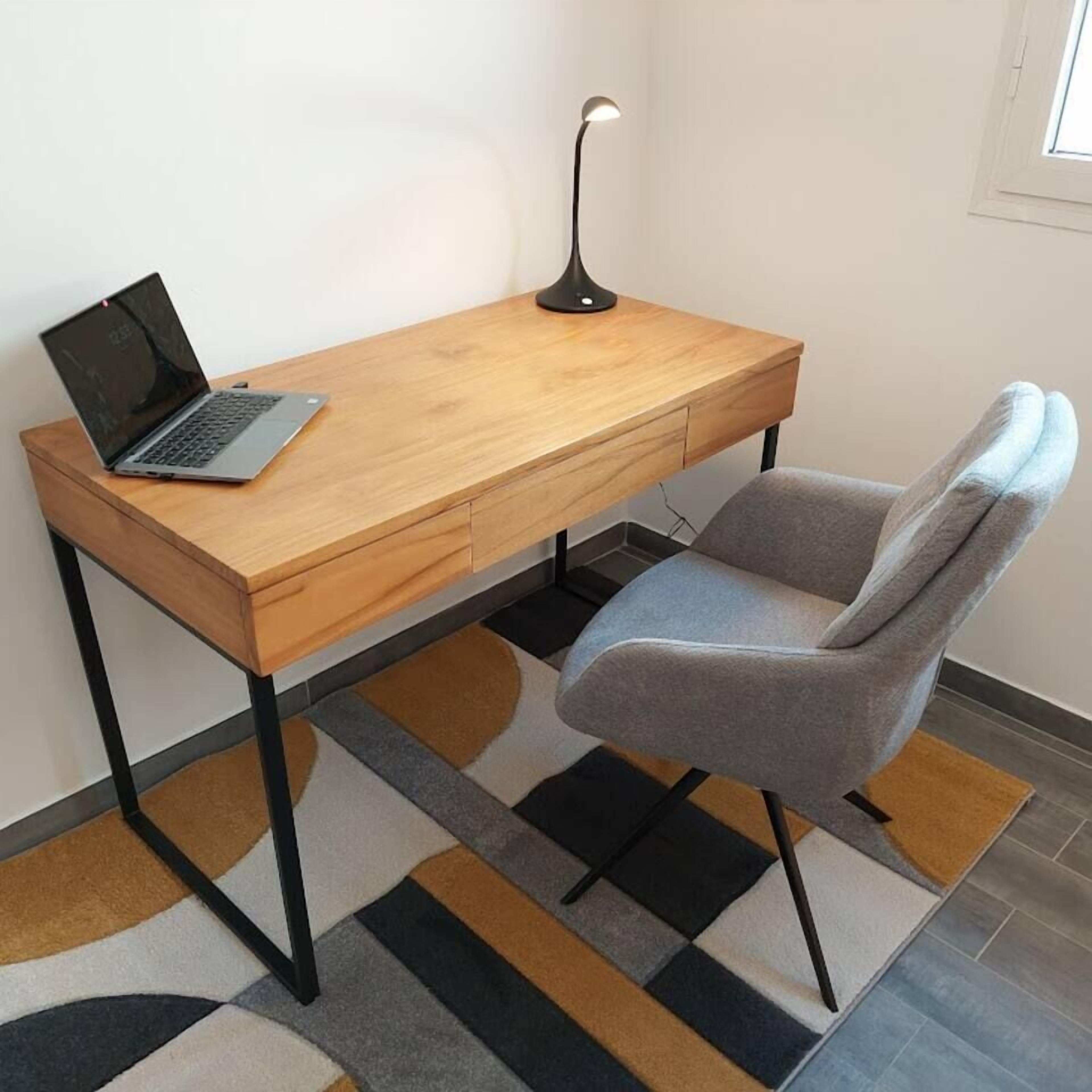A modern workspace with a wooden desk, a laptop, a desk lamp, and a grey office chair.