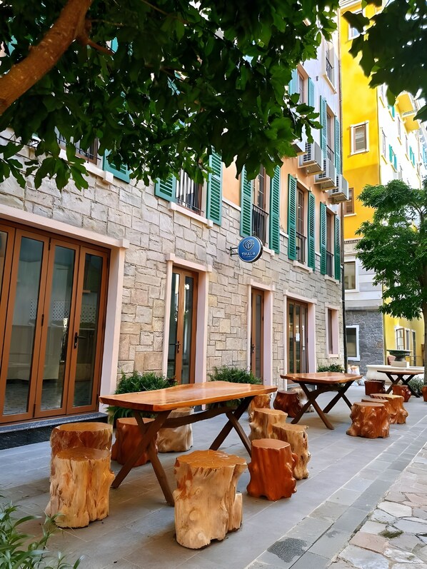 A building with a stone facade, green shutters, and a sign reading "THALA".