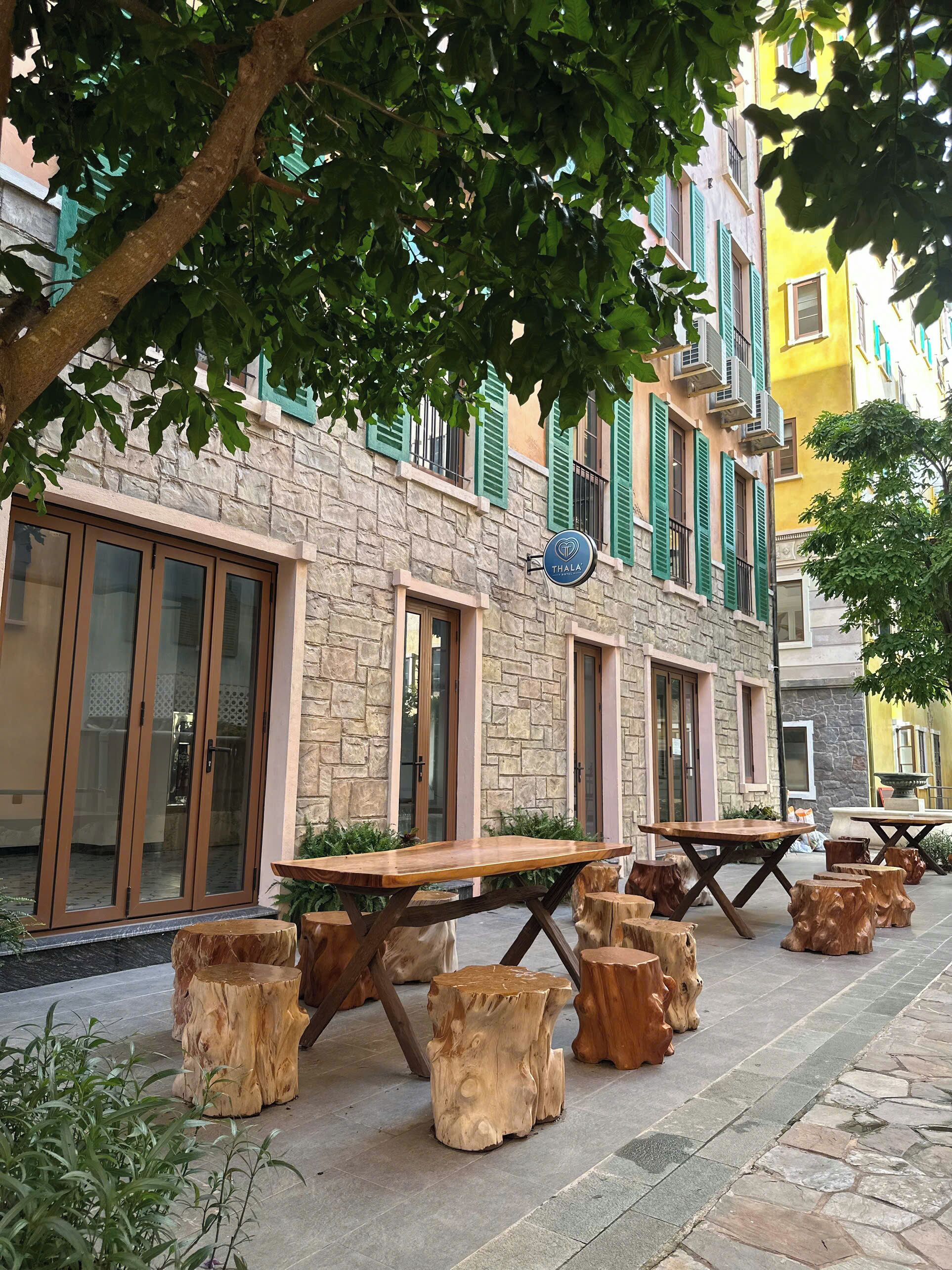 A building with stone facade, green shutters, and a sign reading "Thala".