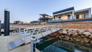 Una moderna proprietà sul lungomare con un ponte, una piscina e un edificio con ampie finestre.