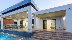 Un hotel moderno con piscina, posti a sedere all'aperto e una terrazza coperta.
