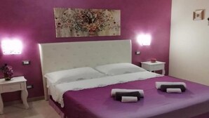 Een slaapkamer met een bed, twee nachtkastjes en een wandlamp.