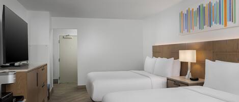 Habitación de hotel con dos camas, televisión, escritorio y una silla.