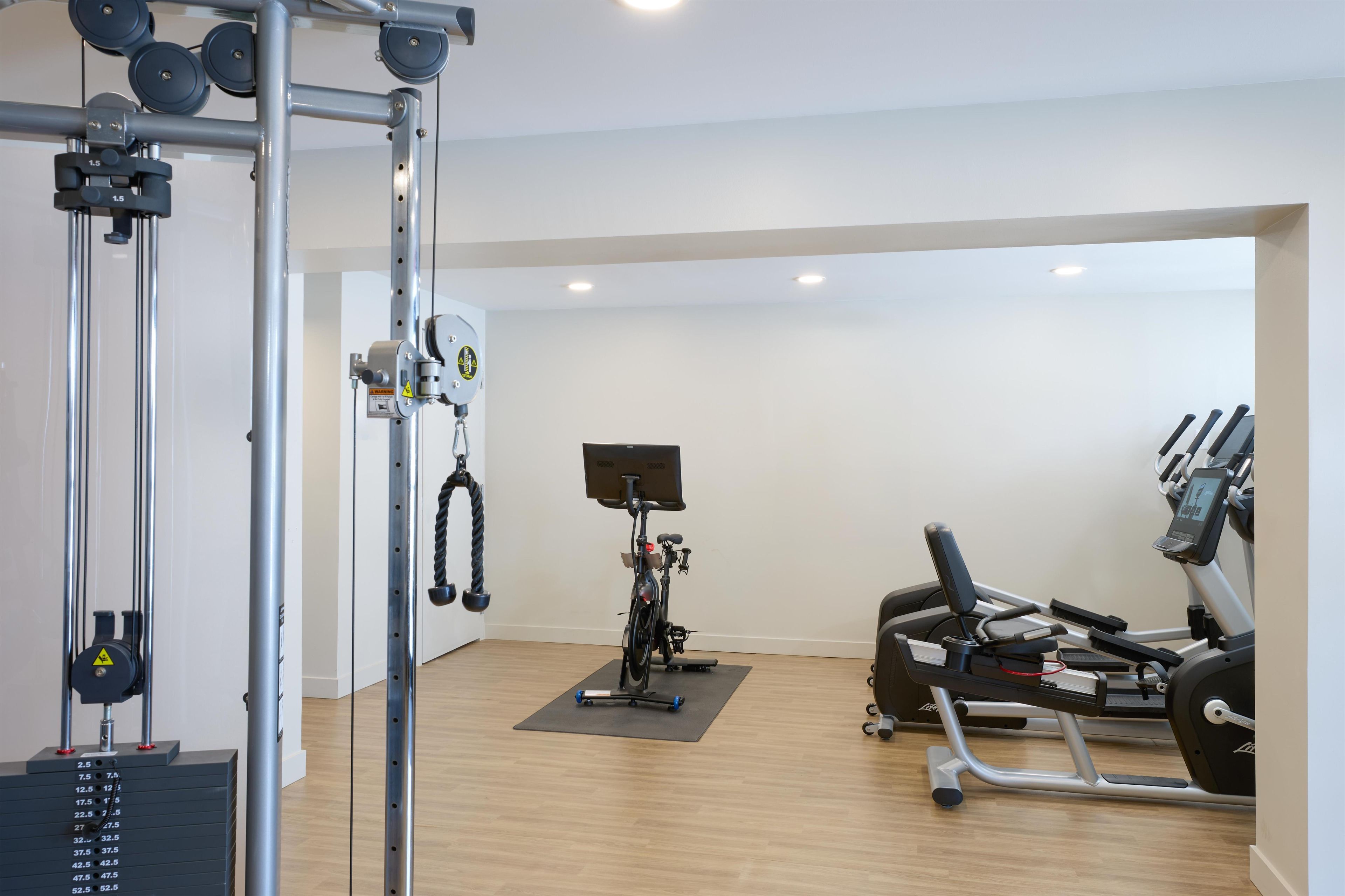Ein Fitnessstudio mit verschiedenen Trainingsgeräten, darunter Laufband, Ergometer und Kraftmaschinen.