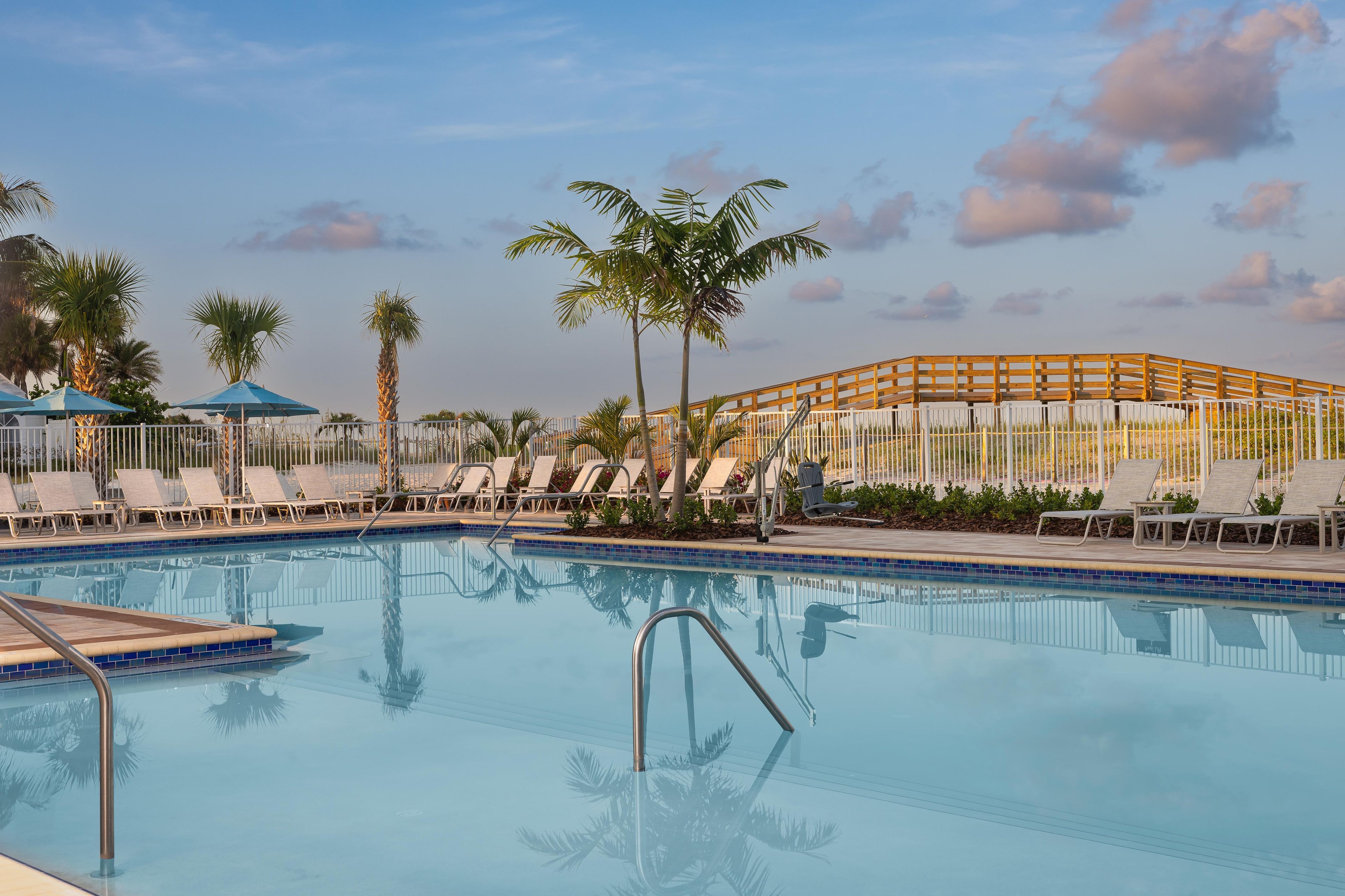 Une piscine avec des chaises longues et des palmiers.