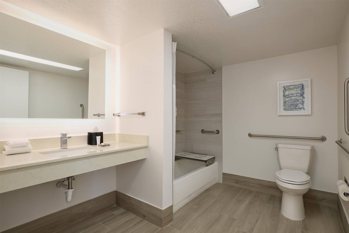 Un baño moderno con lavamanos, espejo, inodoro y ducha.