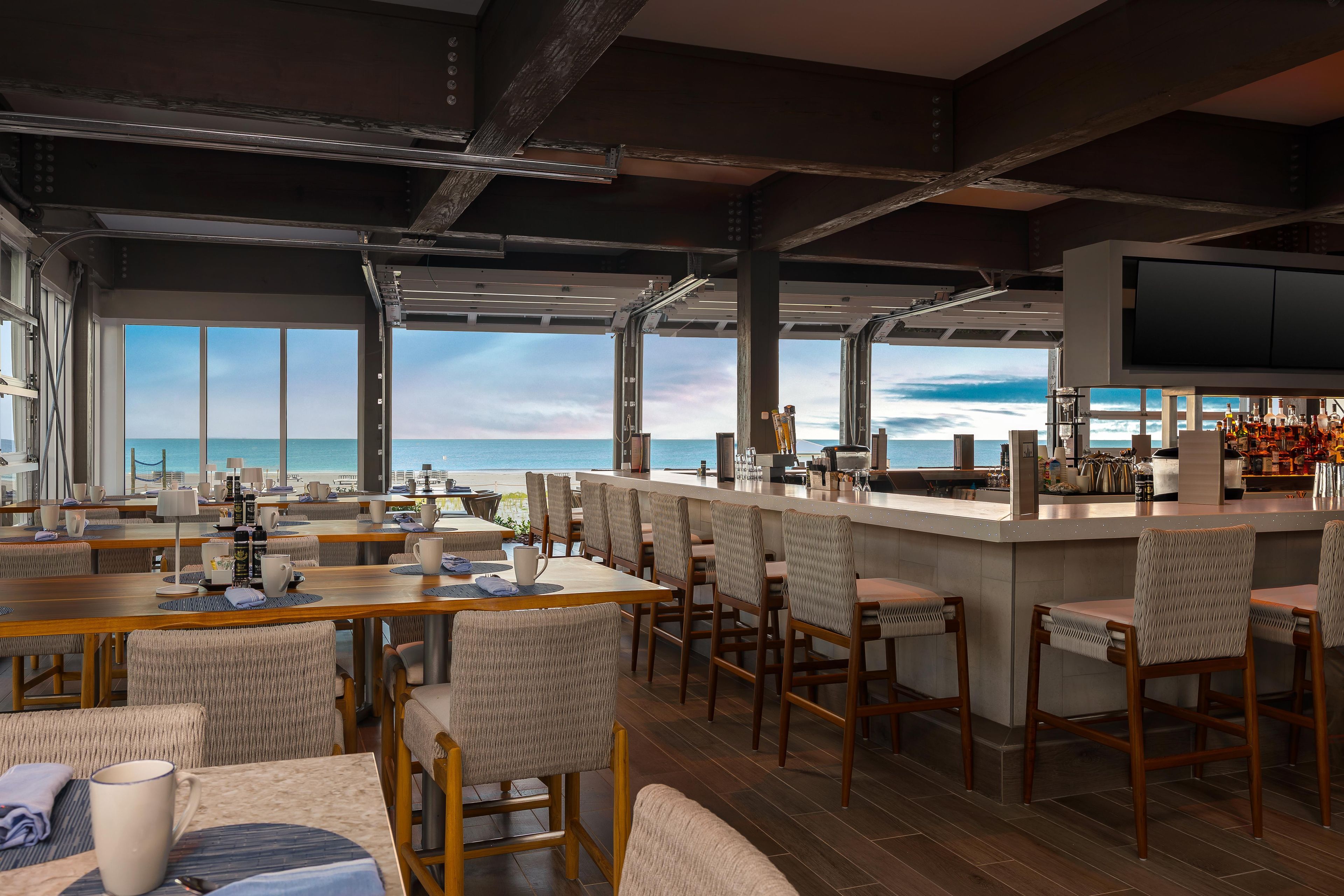 A spacious bar area with a view of the sea, equipped with bar stools and a counter.